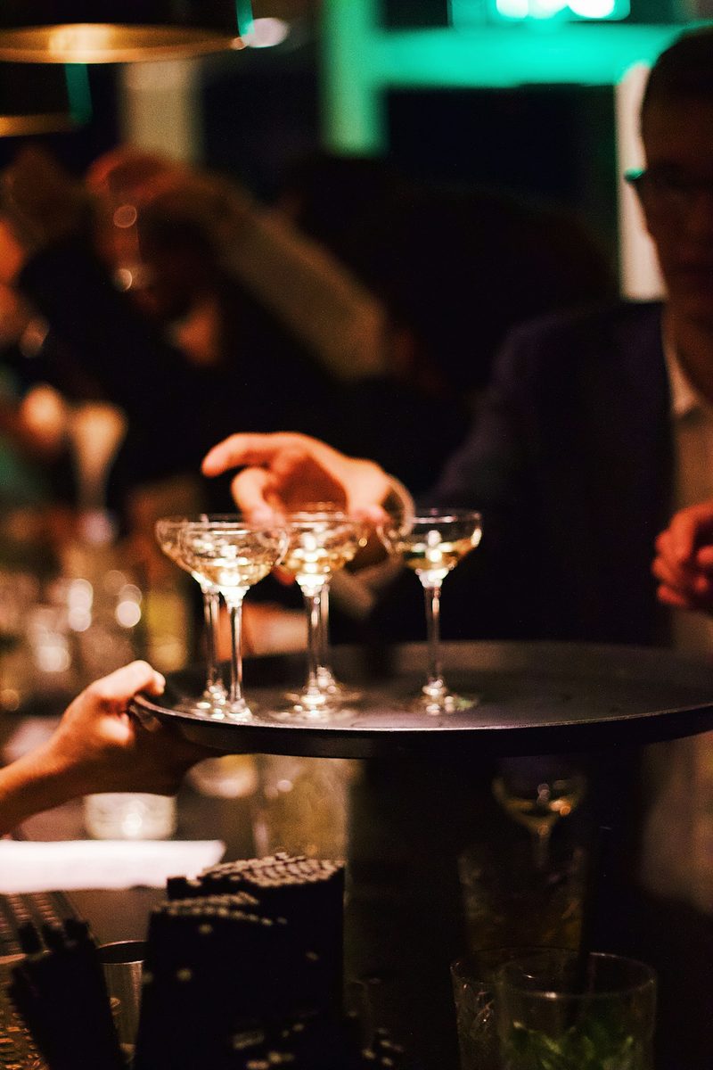 A signature cocktail display with two coupes, a berry kir royale and a framed drinks menu