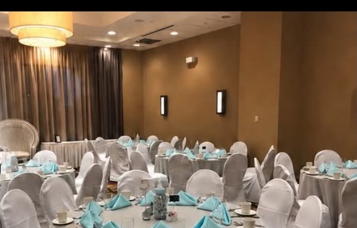 Banquet room styled with white chair covers, set tables and blue napkins